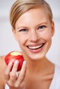 An apple a day is the healthy way. A portrait of a beautiful young woman eating a delicious red apple. Royalty Free Stock Photo