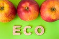 Apple Eco product or food. Three apples are on green background with text eco wooden letters. Example of sustainable environmental