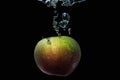 An apple falls into the water on a black background. Royalty Free Stock Photo