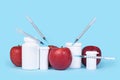 Apple fruits injected with syringes next to pill bottles. Concept for genetically modified food Royalty Free Stock Photo