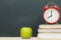 Apple green,alarm clock red on book, put on the desk Royalty Free Stock Photo