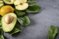 Apple halves, avocado with a stone, whole yellow lemons, ripe green spinach leaves, a blank sheet of Notepad on a gray background
