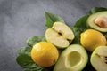 Apple halves, avocado with a stone, whole yellow lemons, ripe green spinach leaves on a gray background