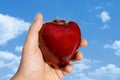 Apple in Hand Against Clouds