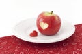 Apple with a heart shaped cut-out on a tablecloth