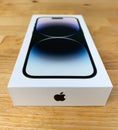 Apple iPhone 14 Pro in box on a wooden table, shallow focus.