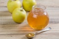 Apple jelly in a jar and apples on wooden background