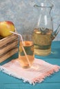 Apple juice in a glass, juice in a jug, apples in a wooden box, colored wooden background. Royalty Free Stock Photo