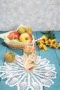 Apple juice in a glass on a lace napkin, juice in a jug, apples on a plate, colored wooden background. Royalty Free Stock Photo