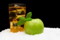 Apple juice,ice cubes and apple with mint on black on snow Royalty Free Stock Photo