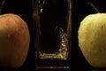 Apple juice pouring in a glass with 2 apple on a black background. Black background with 2 apples, red and green Royalty Free Stock Photo