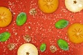 Apple and khaki fruit slices, walnut, spinach leaves, poppy and sesame seeds on red background. Healthy food composition Royalty Free Stock Photo