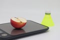 An apple on a kitchen scale against a background of a shuttlecock. Calorie counting. Diet and sports.