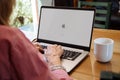 Apple logo in the screen of laptop. Mature woman sitting in front of computer with mac os