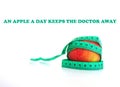 An apple and a measuring tape with text AN APPLE A DAY KEEPS THE DOCTOR AWAY Royalty Free Stock Photo