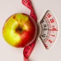 Apple with measuring tape on weight scale. Dieting Royalty Free Stock Photo