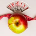 Apple with measuring tape on weight scale. Dieting Royalty Free Stock Photo