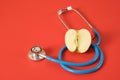 an apple and a medical stethoscope on a bright red background Royalty Free Stock Photo