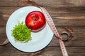 An apple with microgreen on an empty white plate with a tape measure to measure the figure. Diet and raw food concept.