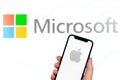 Apple and Microsoft logo. Hand with mobile phone, business concept