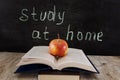 An apple on an open book. The inscription on the board `study at home.` The concept of distance education. Quarantine.