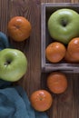 Apple Orange or mandarin in wooden box on brown table.