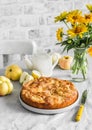 Apple pie, bouquet of yellow flowers, teapot on a light table on a light background in cozy room Royalty Free Stock Photo