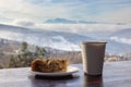 Apple pie and coffee in a paper cup in a shelter overlooking the mountains. Royalty Free Stock Photo