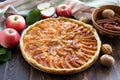 Apple pie with roasted peanuts, fresh apple and caramel sauce on a plate on a dark wooden surface