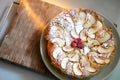 Apple pie sprinkled with icing sugar decorated with raspberries on a plate on a wooden board, top view, copy space Royalty Free Stock Photo