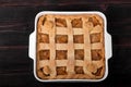 Apple pie in a square ceramic baking sheet on a dark wooden background
