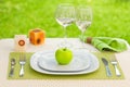 Apple plate with fork and knife against meadow.