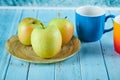 Apple plate and two colorful mugs on blue table