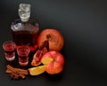 Apple pomegranate liqueur with cinnamon and anise, strong homemade alcohol in two glasses and a bottle on a black background Royalty Free Stock Photo