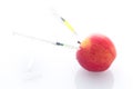 Apple with punched needles and syringes as a concept for modified food white background Royalty Free Stock Photo