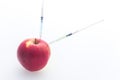 Apple with punched needles and syringes as a concept for modifying food / white background Royalty Free Stock Photo