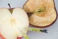 Apple with punched needles and syringes as a concept for modifying food / white background Royalty Free Stock Photo