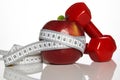 Apple and red colored dumbbells tied with a measuring tape