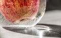 Apple red orange yellow in a vase with water in air bubbles horizontal on the table flare close-up macro Royalty Free Stock Photo