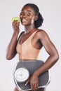 Apple, scale and weightloss with a black woman in studio on a gray background to promote healthy eating or diet. Food Royalty Free Stock Photo