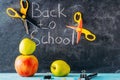 Apple, scissors and school supplies against blackboard with `back to school` on background Royalty Free Stock Photo