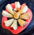 Apple shown beautifully in apple cutter looks like flower shape and it tempts to eat in black background Royalty Free Stock Photo