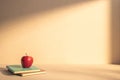 An apple sitting on the top of a stack of books with shadows of the sun. Minimalist background for education concept Royalty Free Stock Photo
