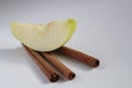 Apple slice a piece of Apple lies on three sticks of cinnamon on a white background