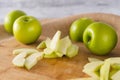 Apple slices close-up on a wooden cutting board. Green apples close-up on a kitchen table