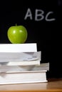 Apple on stack of books in classroom