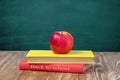 Apple on stack books wooden table blackboard background. Royalty Free Stock Photo