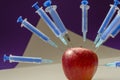 Apple studded with syringes Royalty Free Stock Photo