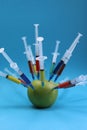 green apple studded with a multi-colored syringe Royalty Free Stock Photo