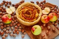 Apple tart on the wooden board decorated with fresh apples, hazelnuts and spices - anise stars and cinnamon on the gray table Royalty Free Stock Photo